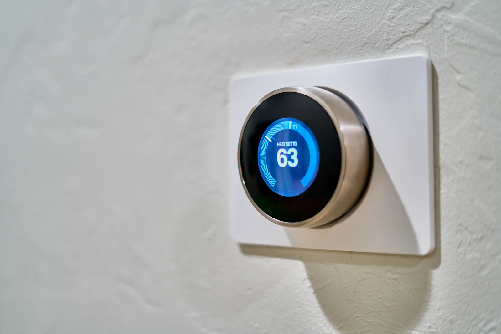 A smart thermostat on a wall set to 63 degrees