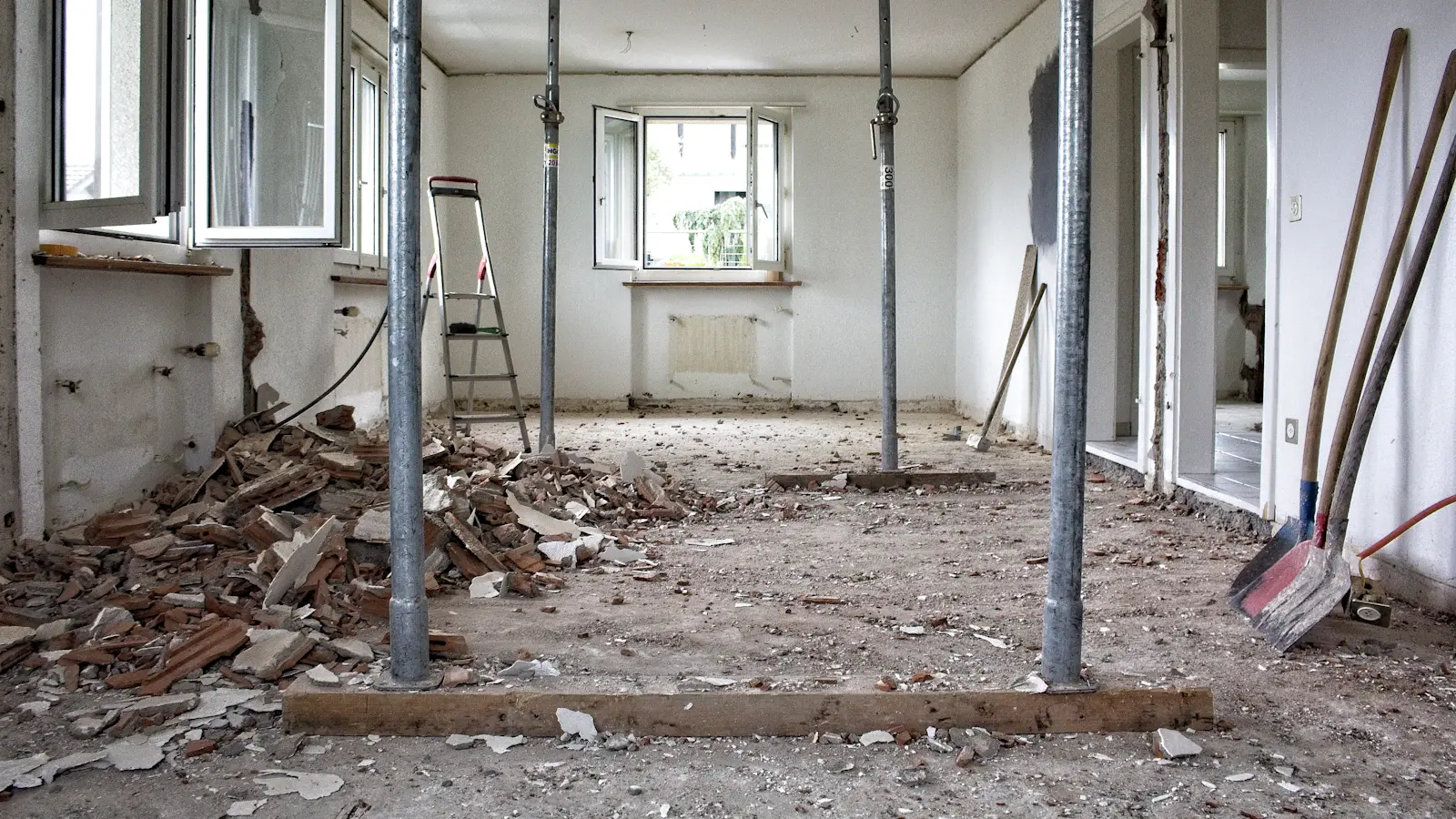 A room stripped back to the walls, with props holding the ceiling and debris on the floor