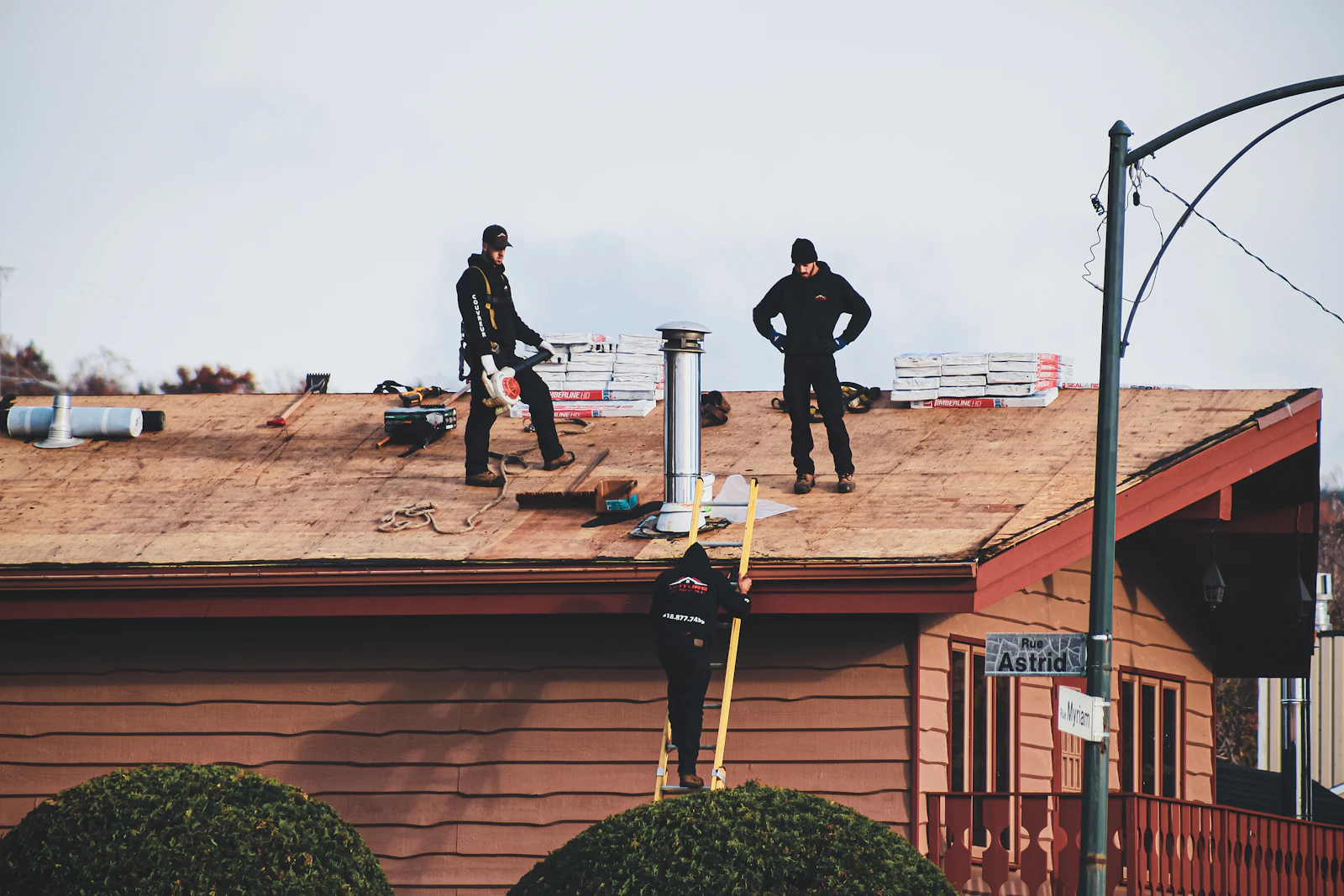 A roof tear-off down to the wood deck, with roofers at work