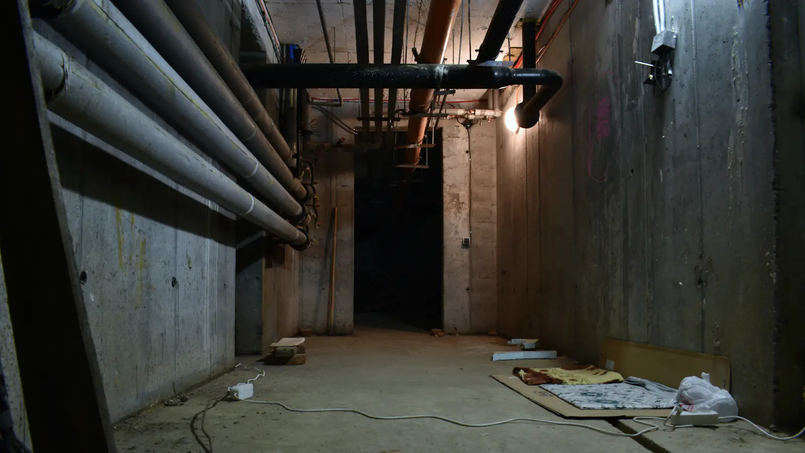 A dark basement with pipes along the ceiling