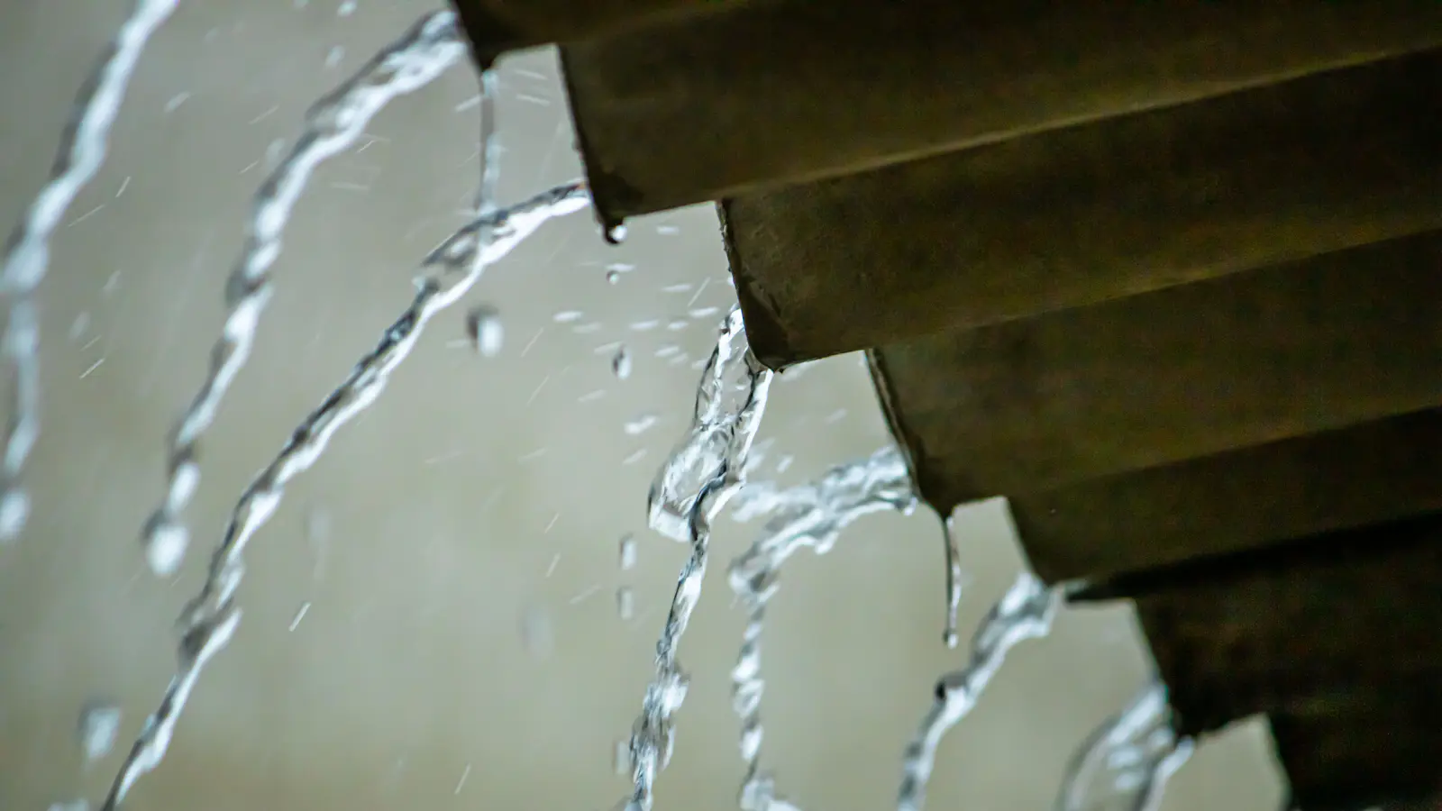 Water pouring off the edge of a roof in heavy rain