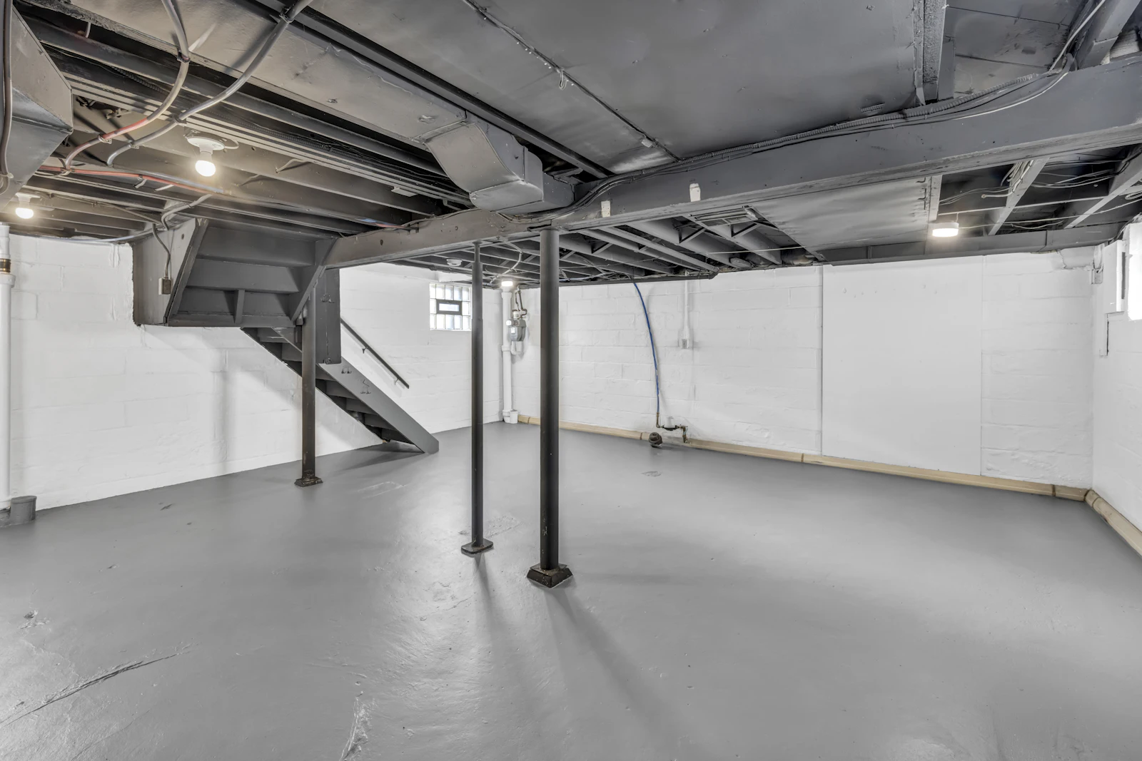 A clean, dry basement with sealed walls, a painted floor and open joists